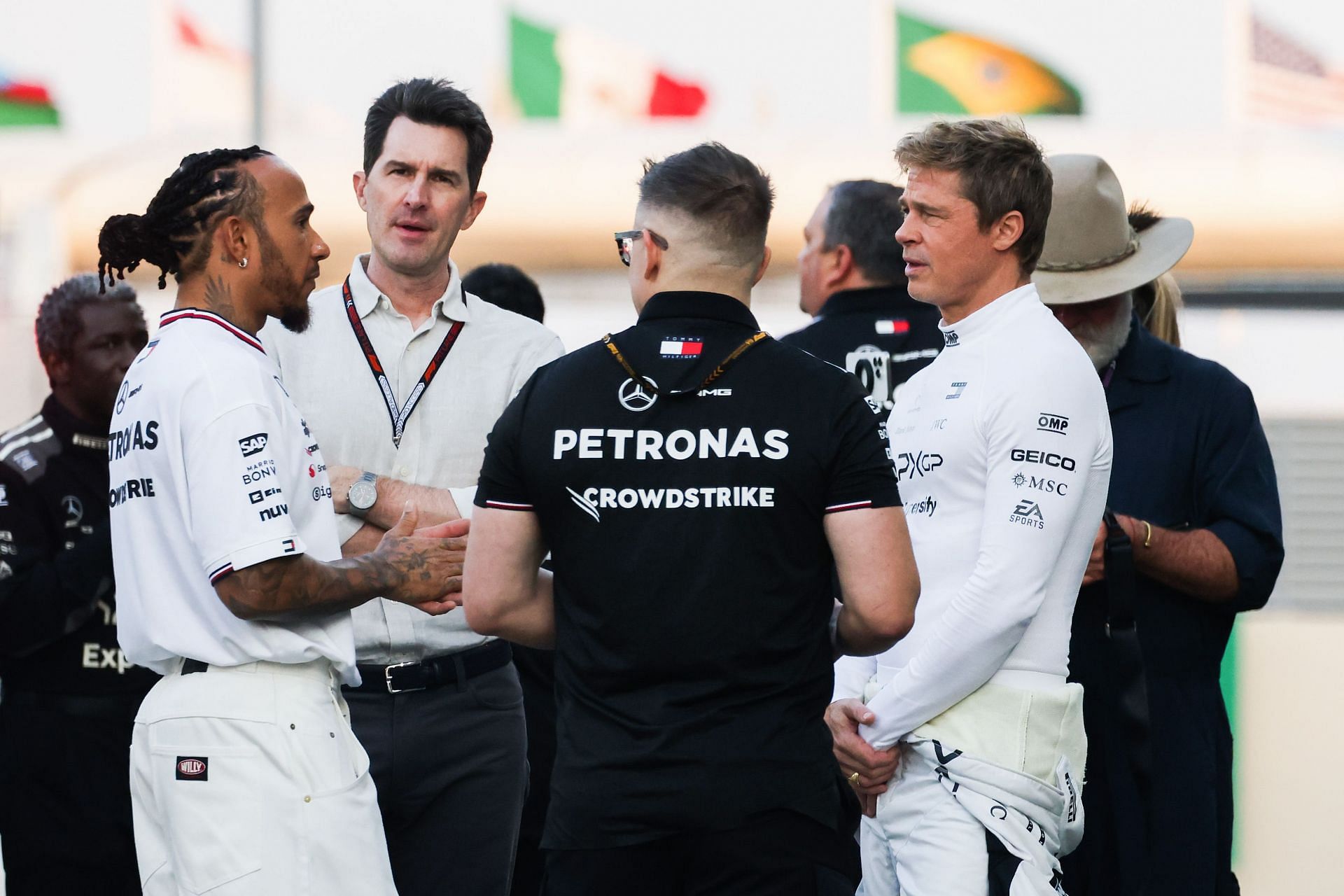 Lewis Hamilton of Mercedes, Brad Pitt, actor playing Sonny Hayes, a driver of the fictional Apex APXGP F1 team in the upcoming 'F1' movie, and Joseph Kosinski, the director of the movie, are talking on a movie set - Source: Getty